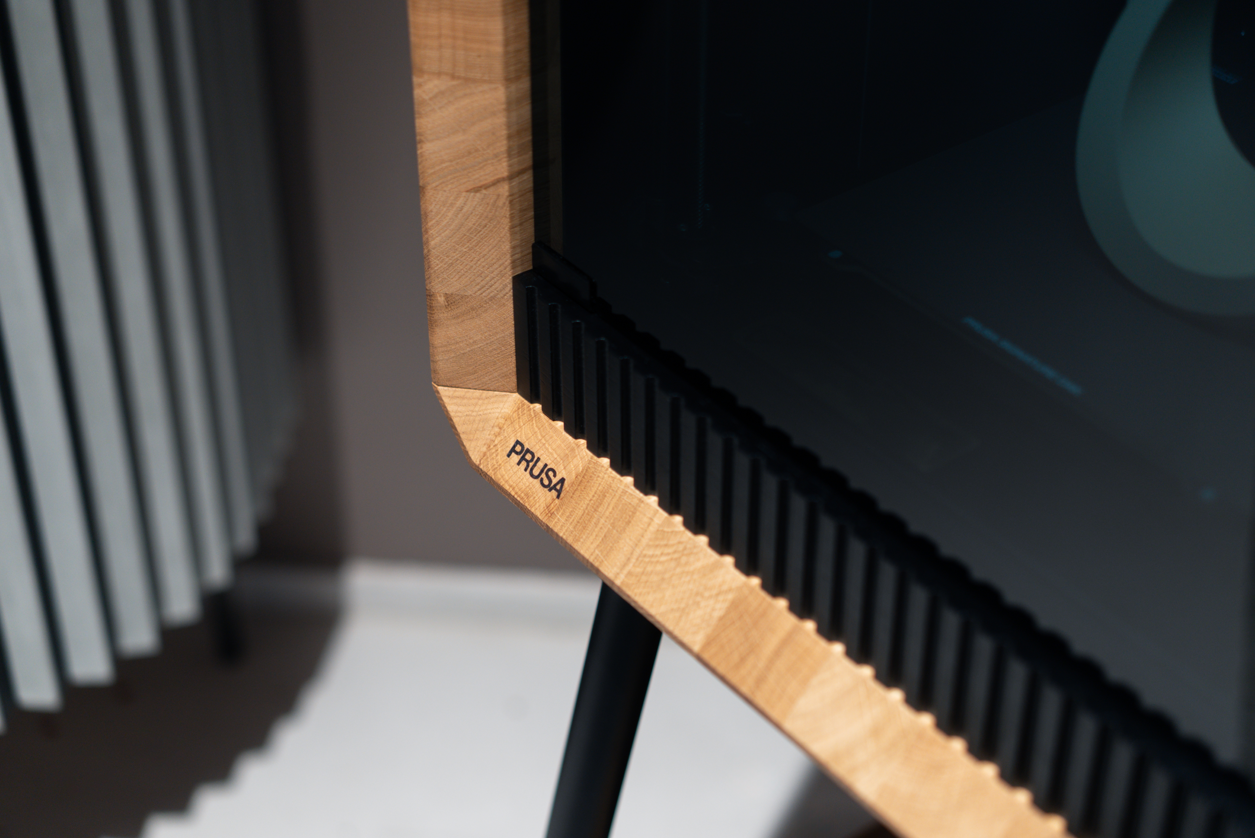 Szczegół narożnika z drewna dębowego w drukarce Prusa Signature Oak, ukazujący naturalne usłojenie drewna oraz logo marki PRUSA